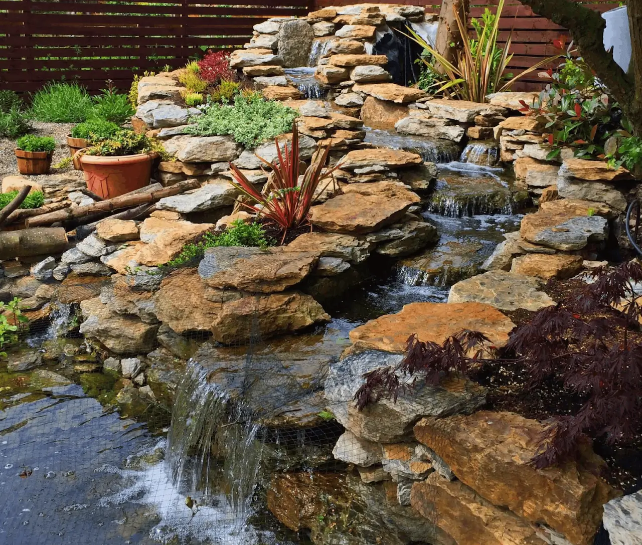 Water fall built in a backyard water feature design by Omni Landscape.